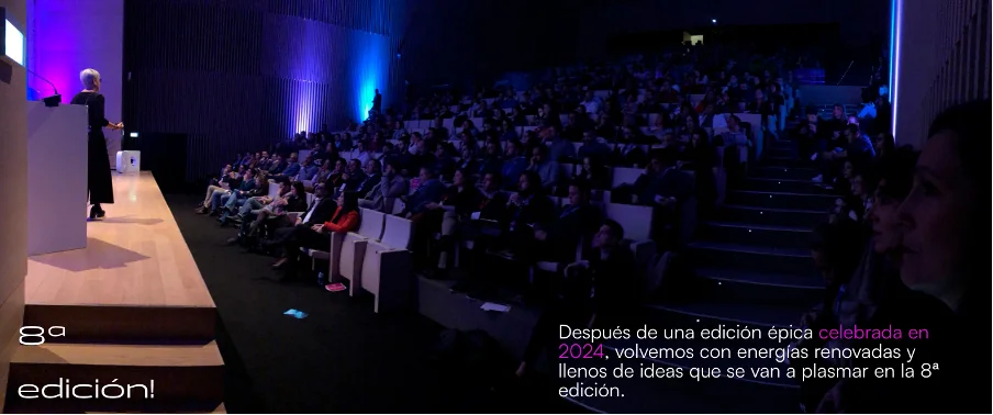 Foto de un auditorio con varios asistentes y una ponente.