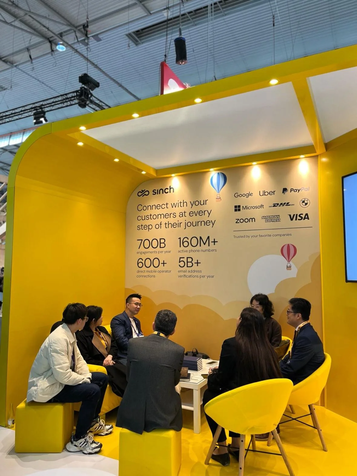 Grupo de personas reunidas en un estand amarillo en MWC Barcelona.